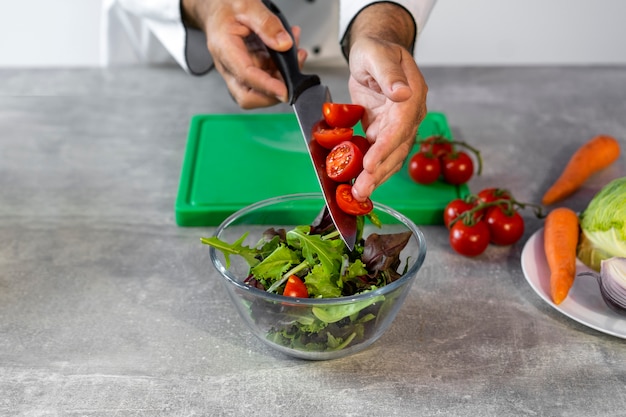 Foto gratuita chef masculino en la cocina preparando ensalada