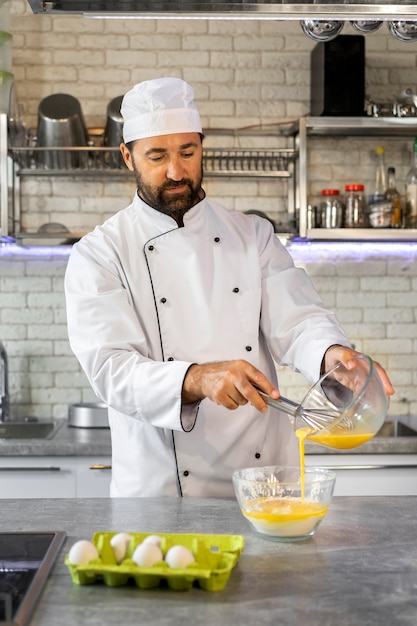 Foto gratuita chef masculino en la cocina usando huevos para cocinar