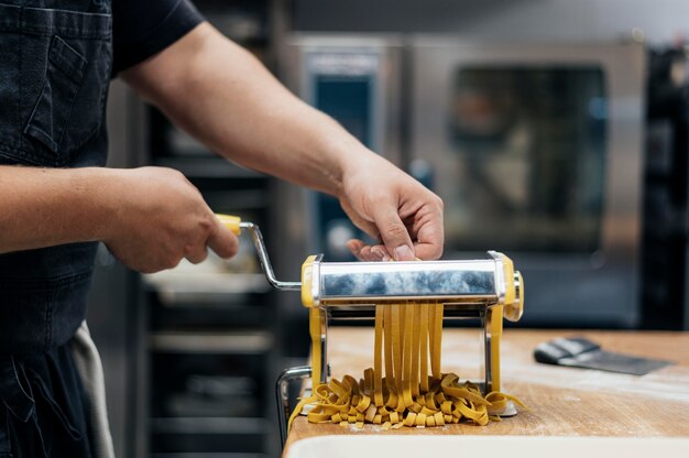 Chef masculino con máquina para picar masa de pasta fresca