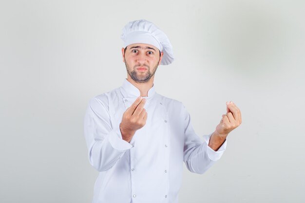 Chef masculino mostrando gesto con las manos en uniforme blanco y mirando confundido