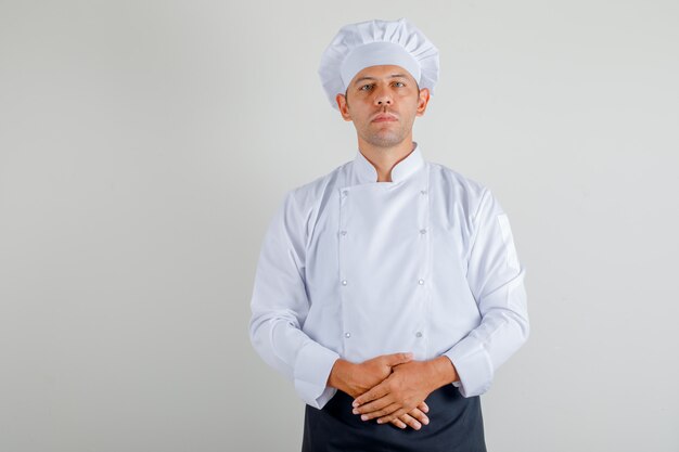 Chef masculino de pie listo para cocinar en uniforme, delantal y sombrero