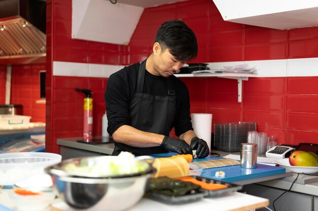 Chef masculino preparando un pedido de sushi para llevar