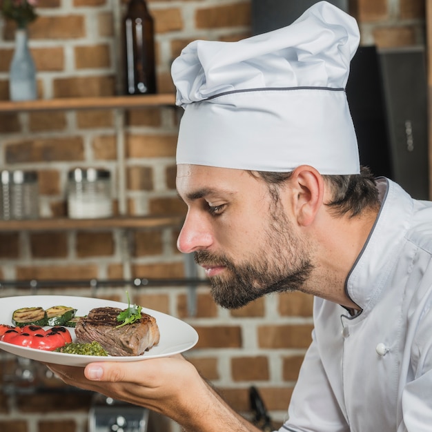 Foto gratuita chef masculino que huele el delicioso plato preparado