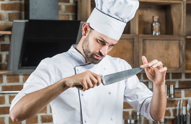Chef masculino tocando la nitidez del cuchillo
