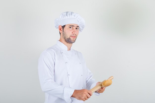 Chef masculino en uniforme blanco con cuchara de madera y rodillo