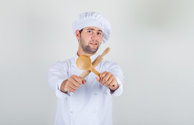 Chef masculino en uniforme blanco con cuchara de madera y rodillo