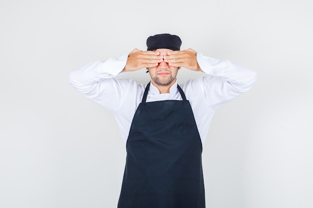 Foto gratuita chef masculino en uniforme, delantal cubriendo los ojos con las manos, vista frontal.