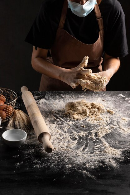 Chef mezclando la masa sobre la mesa con harina