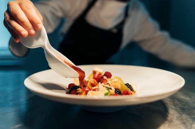 Foto gratuita chef mujer añadiendo salsa al plato