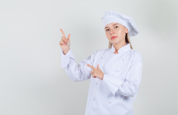 Chef mujer apuntando al lado con gesto de pistola en uniforme blanco