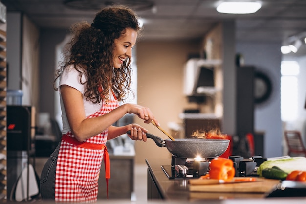 Chef mujer cocinar verduras en sartén