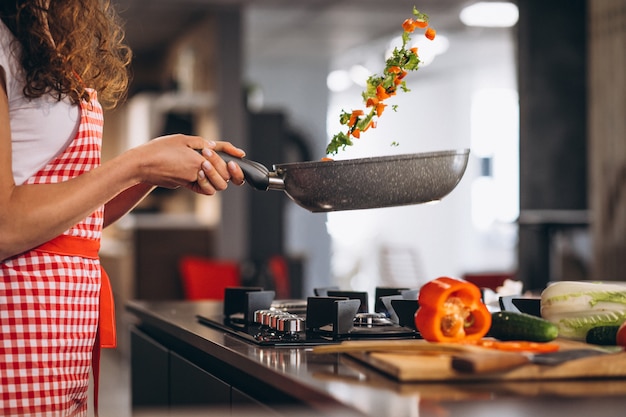 Chef mujer cocinar verduras en sartén