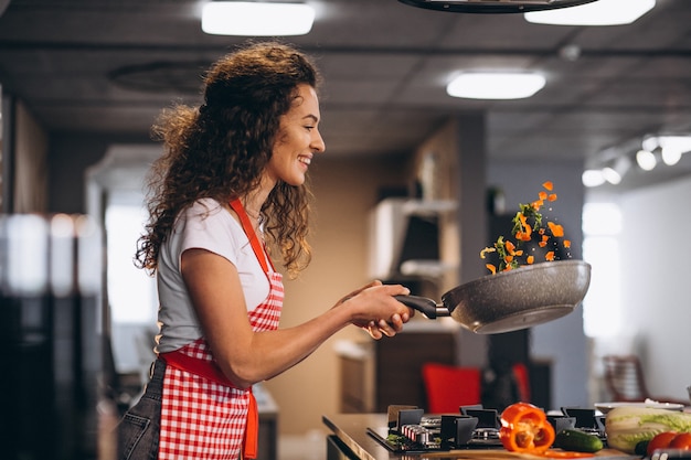 Chef mujer cocinar verduras en sartén