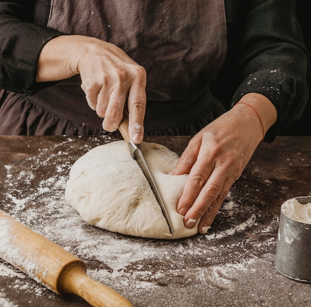 Foto gratuita chef mujer cortando la masa de pizza por la mitad