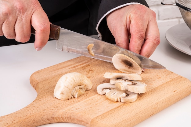 Chef mujer cortando setas en la tabla de cortar