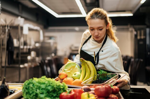 Chef mujer con delantal y bandeja de fruta