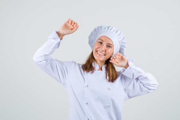 Chef mujer estirando los brazos en uniforme blanco y mirando alegre