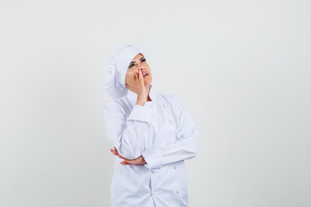 Foto gratuita chef mujer gritando a alguien mientras mira hacia arriba en uniforme blanco