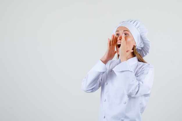 Chef mujer gritando en voz alta en uniforme blanco y con aspecto optimista