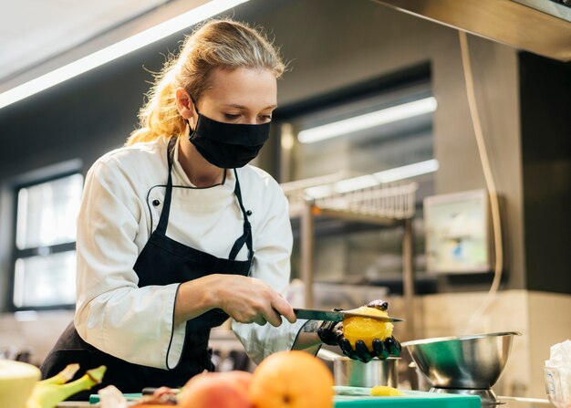 Chef mujer con máscara rebanar fruta