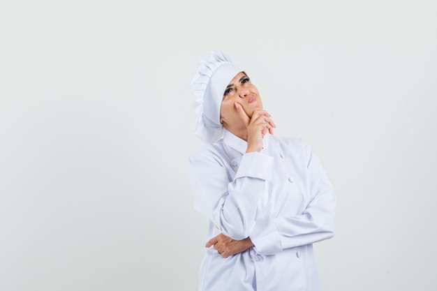 Chef mujer mirando hacia arriba en uniforme blanco y mirando indeciso