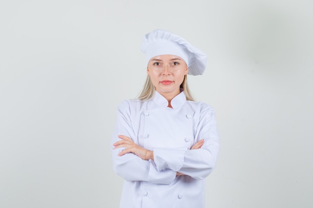 Chef mujer mirando a la cámara con los brazos cruzados en uniforme blanco y mirando positivo