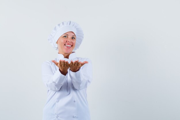 Chef mujer mostrando algo a alguien con uniforme blanco y mirando complacido