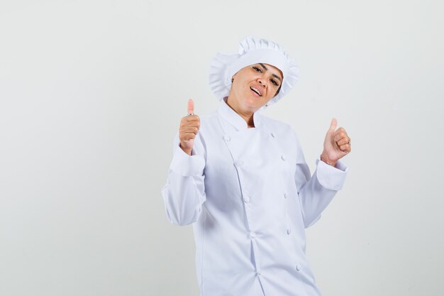 Chef mujer mostrando doble pulgar hacia arriba en uniforme blanco y mirando confiado