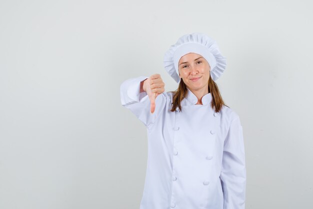 Chef mujer mostrando el pulgar hacia abajo y sonriendo en uniforme blanco