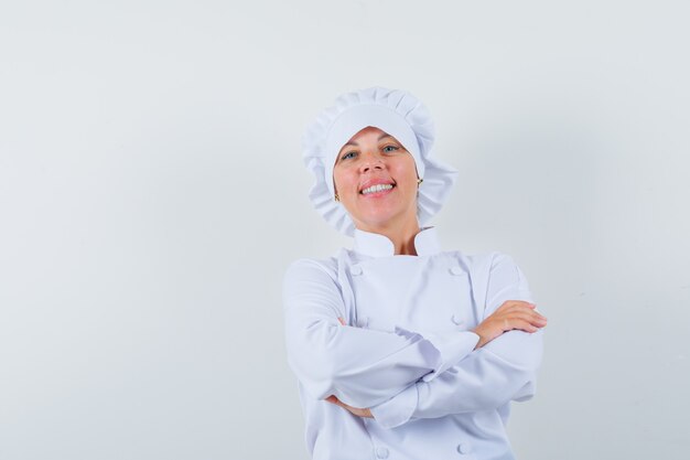 Chef mujer de pie con los brazos cruzados en uniforme blanco y mirando confiado
