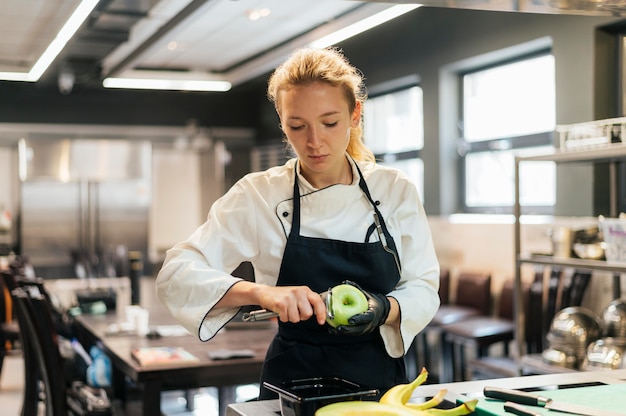 Chef mujer quitando piel de manzana