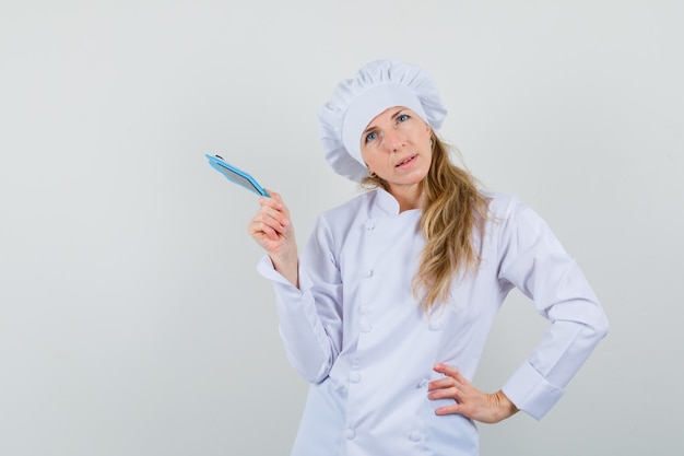 Foto gratuita chef mujer sosteniendo mini portapapeles en uniforme blanco