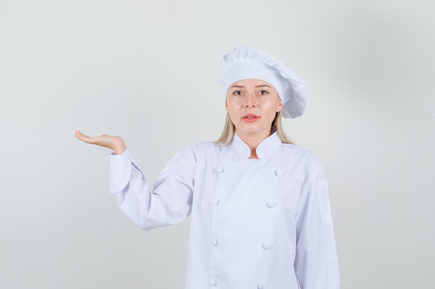 Chef mujer en uniforme blanco gesticulando como sosteniendo algo