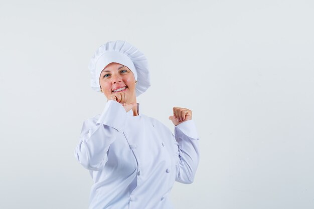 Chef mujer en uniforme blanco mostrando gesto ganador y mirando contento