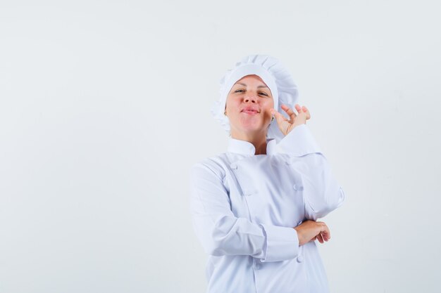 Chef mujer en uniforme blanco mostrando gesto zip y buscando espacio asegurado para texto