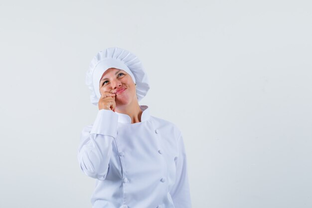 Chef mujer en uniforme blanco mostrando gesto zip y mirando tranquilo