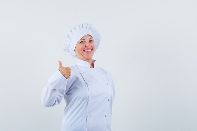 Chef mujer en uniforme blanco mostrando el pulgar hacia arriba y mirando contento