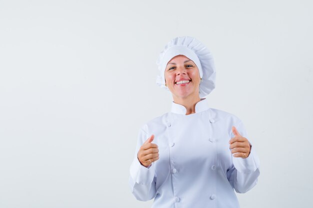 Chef mujer en uniforme blanco mostrando el pulgar hacia arriba y mirando contento