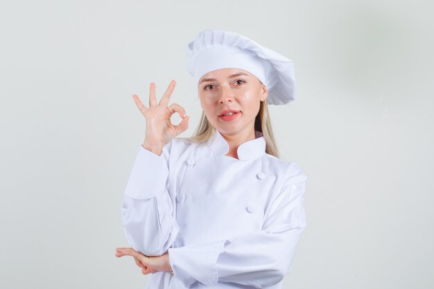 Chef mujer en uniforme blanco mostrando signo ok y mirando positivo