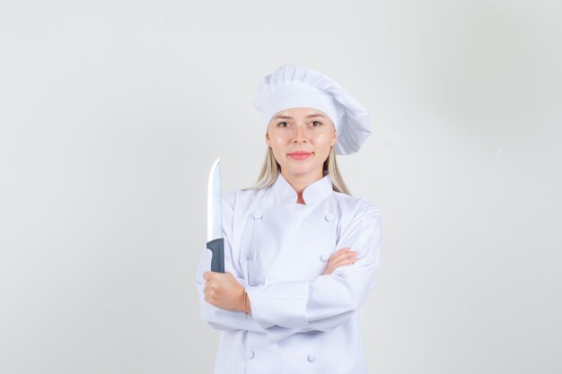 Chef mujer en uniforme blanco sosteniendo un cuchillo y sonriendo