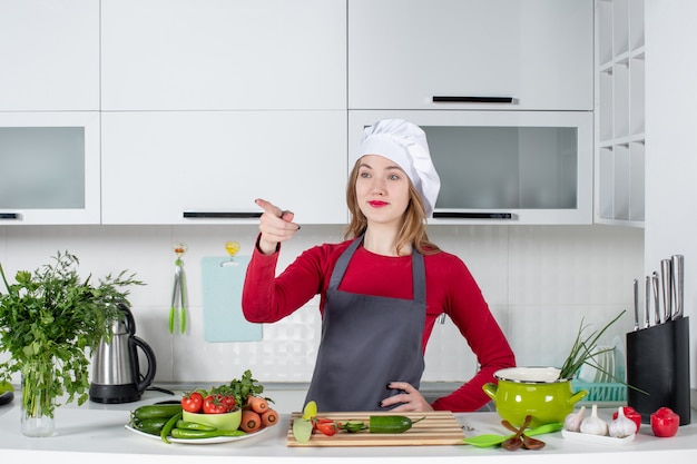 Chef mujer vista frontal en sombrero de cocinero poniendo la mano en la cintura