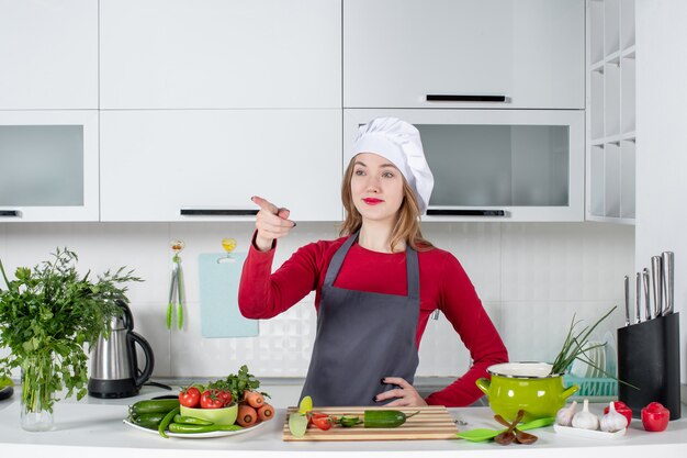 Chef mujer vista frontal en sombrero de cocinero poniendo la mano en la cintura