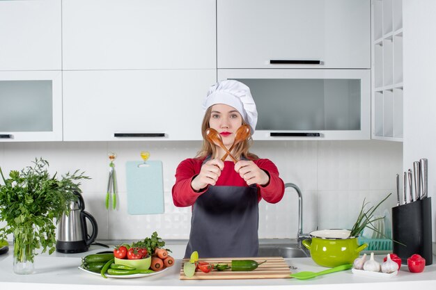 Chef mujer vista frontal en sombrero de cocinero sosteniendo cucharas cruzadas