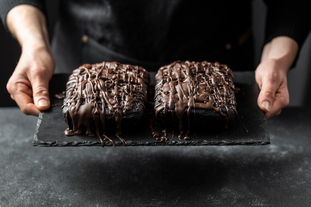 Chef pastelero sosteniendo dos pasteles de chocolate