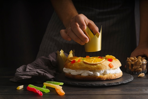 Chef poniendo corona de papel en el postre del día de la epifanía