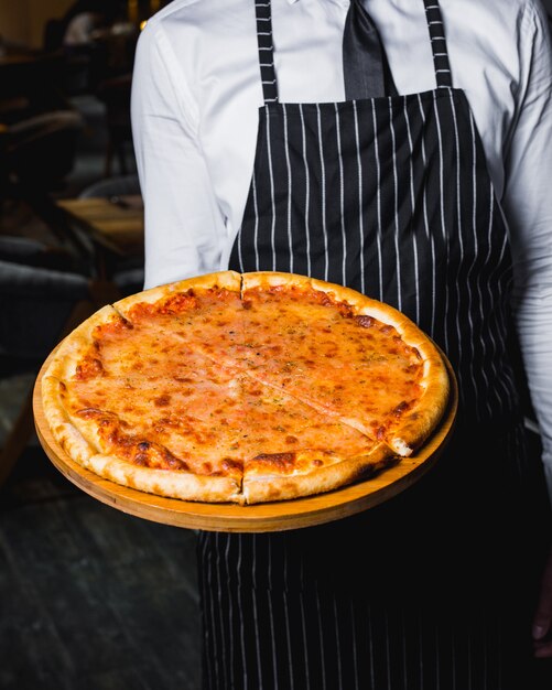 Chef presenta pizza margherita en tablero de madera