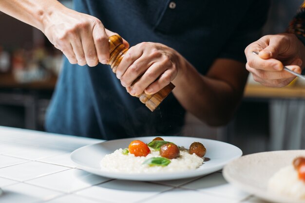 Chef profesional prepara un delicioso plato humeante de risotto de parmesano italiano en una cocina de diseñador hipster