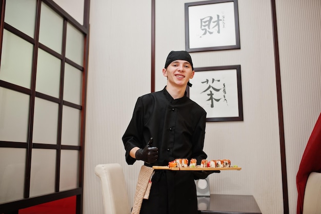 Chef profesional vestido de negro con sushi y rollos en un restaurante de comida tradicional japonesa