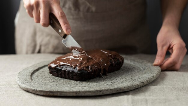 Chef de repostería cortando en pastel de chocolate