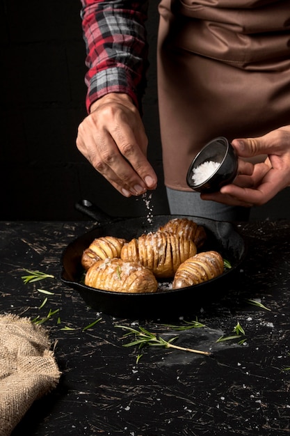 Chef rociando sal sobre papas en una sartén